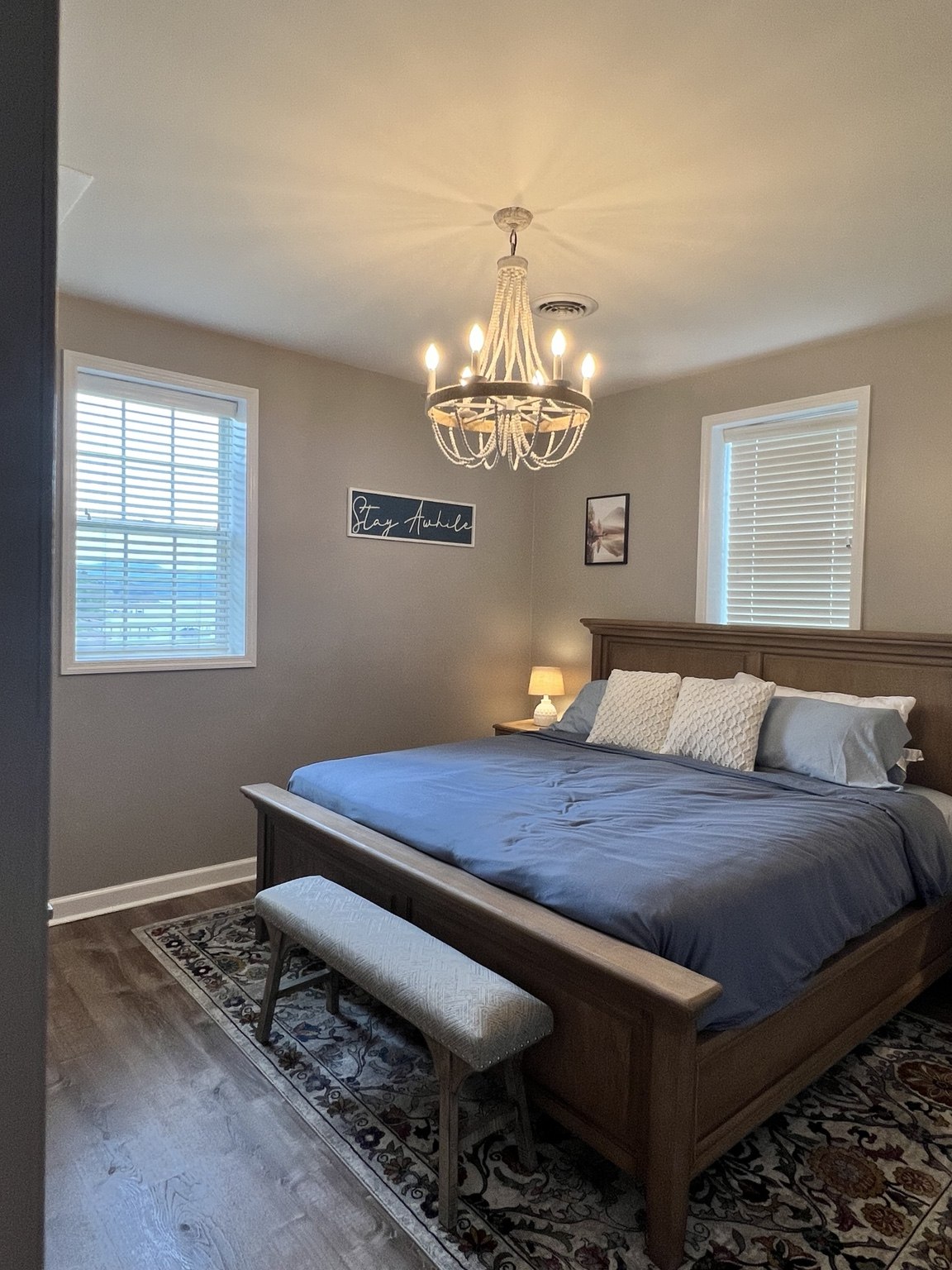 Second king bedroom with wood bed frame, chandelier and upholstered bench
