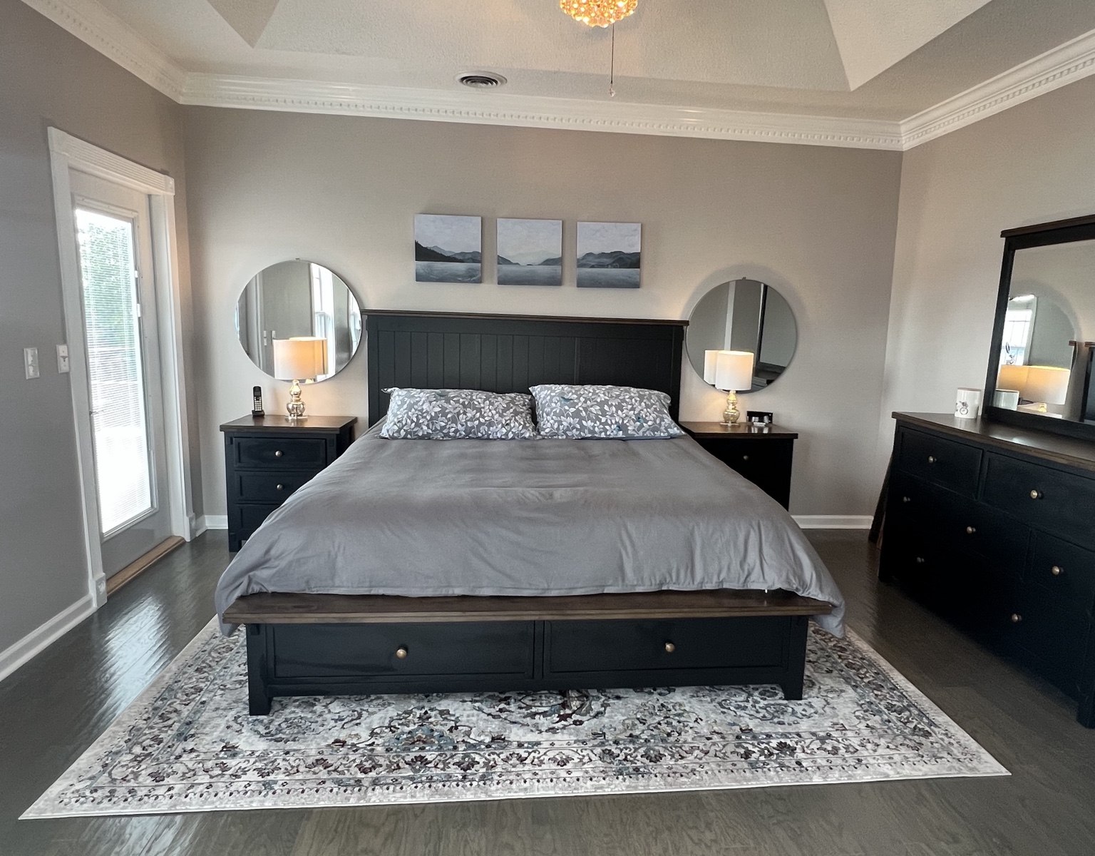 King bedroom with tray ceiling, dark furniture and windows